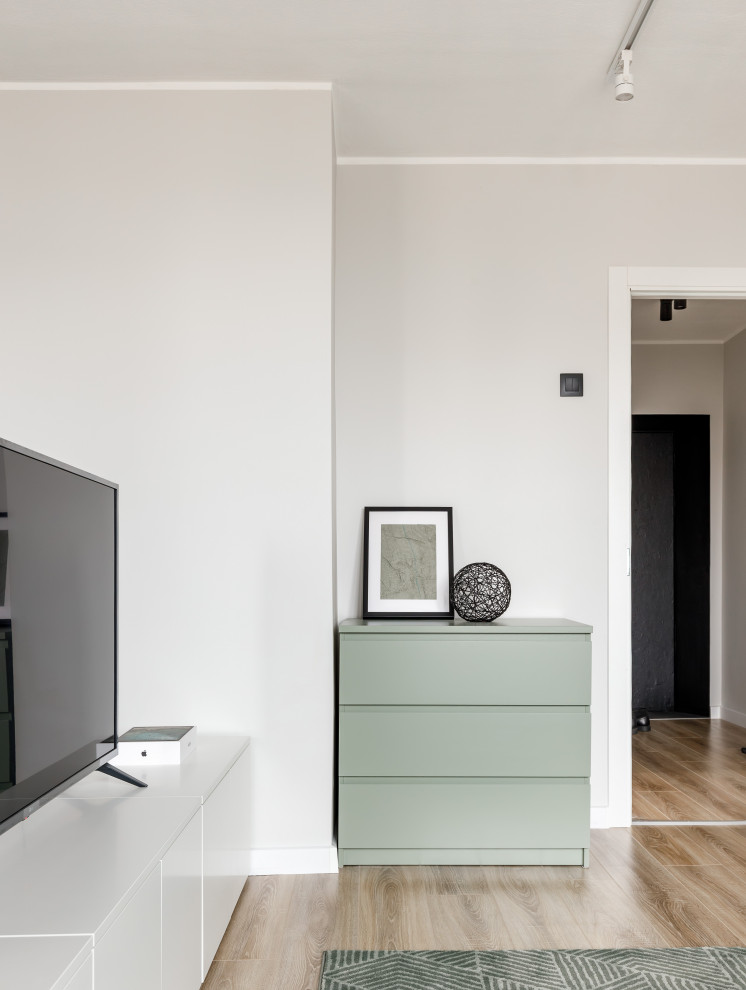Источник вдохновения для домашнего уюта: маленькая открытая, объединенная гостиная комната в современном стиле с зелеными стенами, полом из ламината, отдельно стоящим телевизором и коричневым полом для на участке и в саду