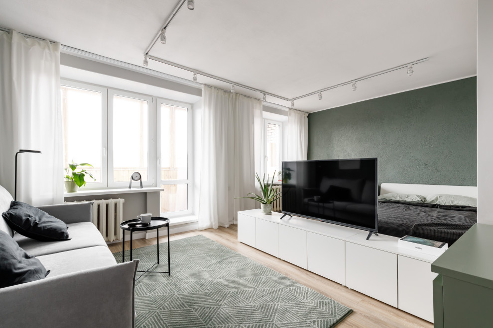Свежая идея для дизайна: маленькая открытая, объединенная гостиная комната в современном стиле с зелеными стенами, полом из ламината, отдельно стоящим телевизором и коричневым полом для на участке и в саду - отличное фото интерьера