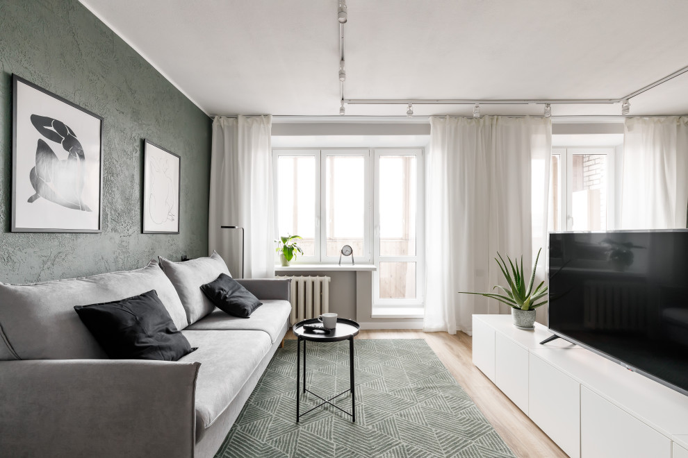 Immagine di un piccolo soggiorno contemporaneo aperto con pareti verdi, pavimento in laminato, TV autoportante e pavimento marrone
