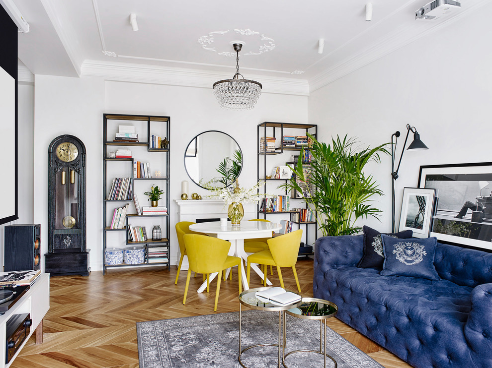 Стильный дизайн: парадная, изолированная гостиная комната в стиле фьюжн с белыми стенами, паркетным полом среднего тона, стандартным камином и синим диваном - последний тренд