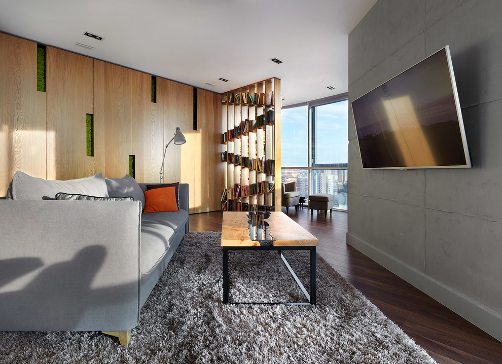 Diseño de salón para visitas abierto contemporáneo con paredes grises, suelo de madera oscura, televisor colgado en la pared y suelo marrón