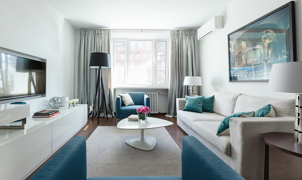 Стильный дизайн: парадная, изолированная гостиная комната в современном стиле с белыми стенами, паркетным полом среднего тона, телевизором на стене и коричневым полом - последний тренд
