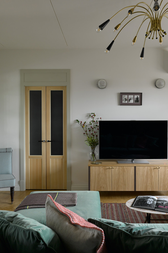 Modern inredning av ett vardagsrum, med vita väggar, mellanmörkt trägolv, en fristående TV och brunt golv