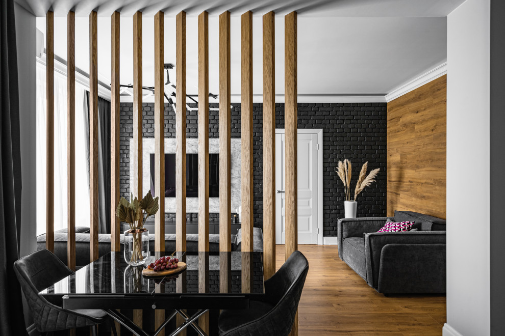 Imagen de salón actual de tamaño medio con paredes negras, suelo de madera en tonos medios, televisor colgado en la pared, bandeja y ladrillo