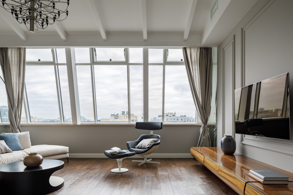 Esempio di un soggiorno design con pareti grigie, parquet scuro, TV a parete e pavimento marrone