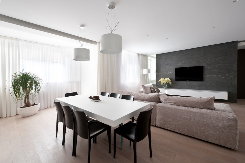 Стильный дизайн: большая открытая гостиная комната в современном стиле с серыми стенами, полом из ламината и телевизором на стене - последний тренд
