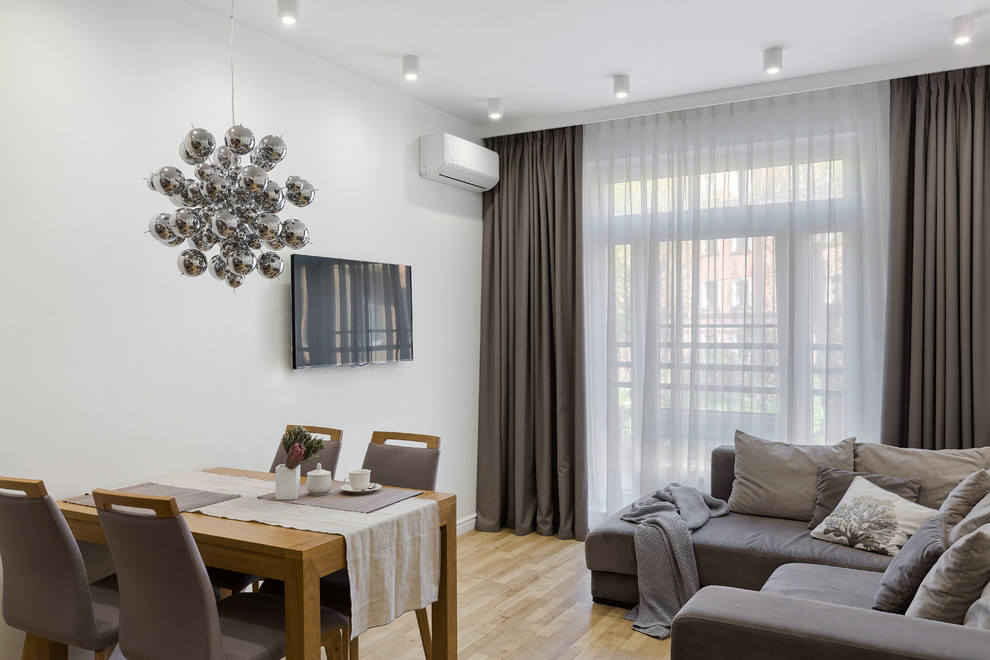 Источник вдохновения для домашнего уюта: гостиная комната в современном стиле с белыми стенами, полом из ламината, телевизором на стене и коричневым полом