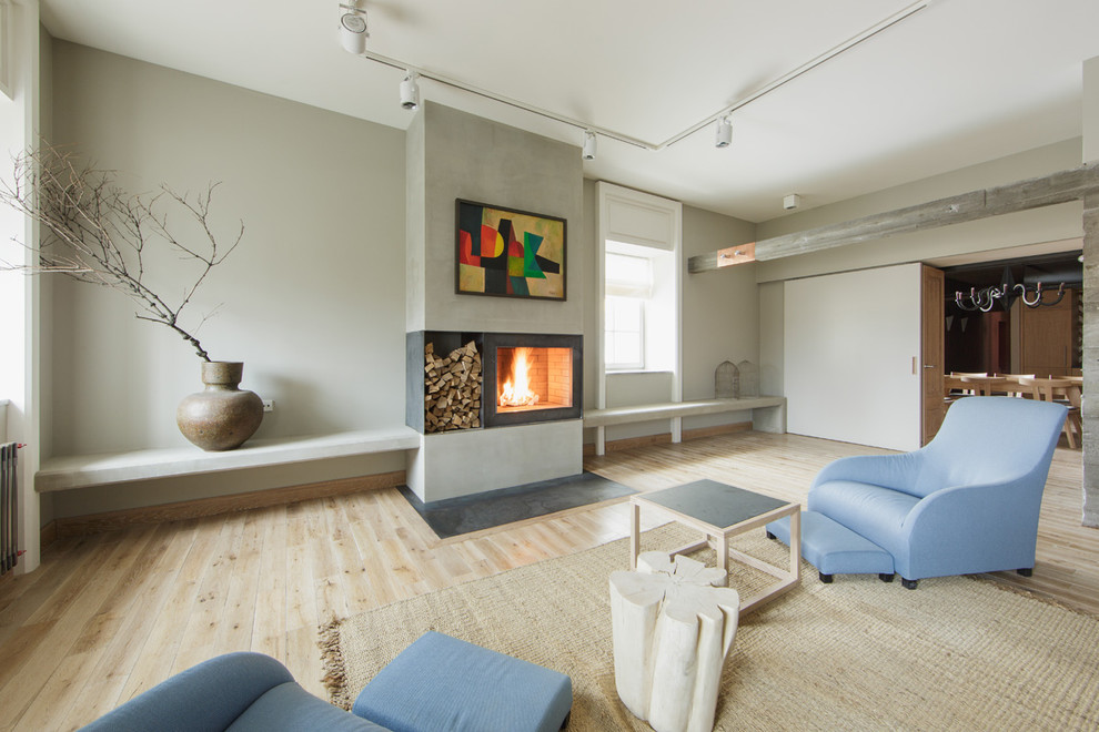 На фото: объединенная гостиная комната в скандинавском стиле с серыми стенами, светлым паркетным полом и стандартным камином без телевизора