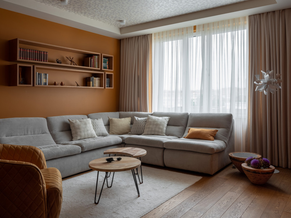 Стильный дизайн: гостиная комната в современном стиле с оранжевыми стенами, паркетным полом среднего тона и коричневым полом - последний тренд