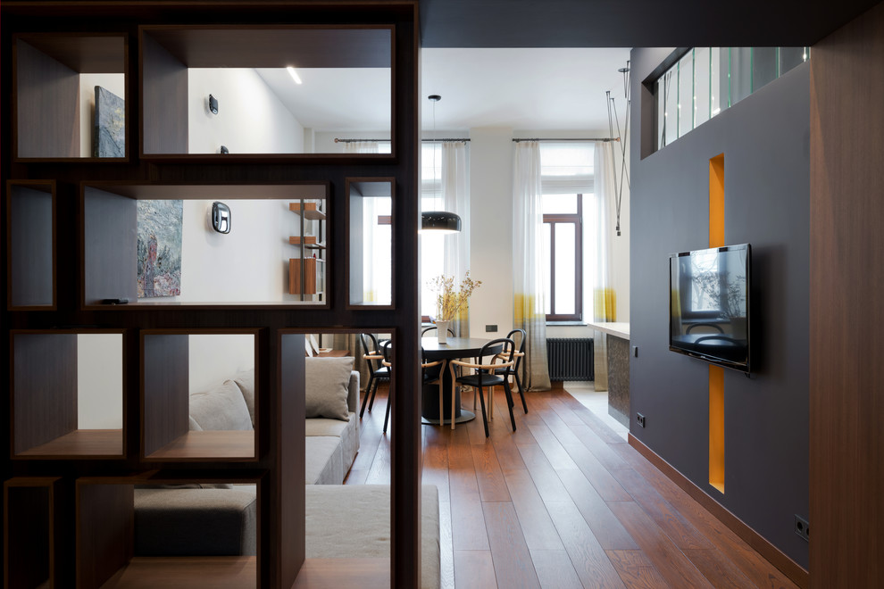 Immagine di un grande soggiorno aperto con pavimento in legno massello medio, pareti bianche e TV a parete