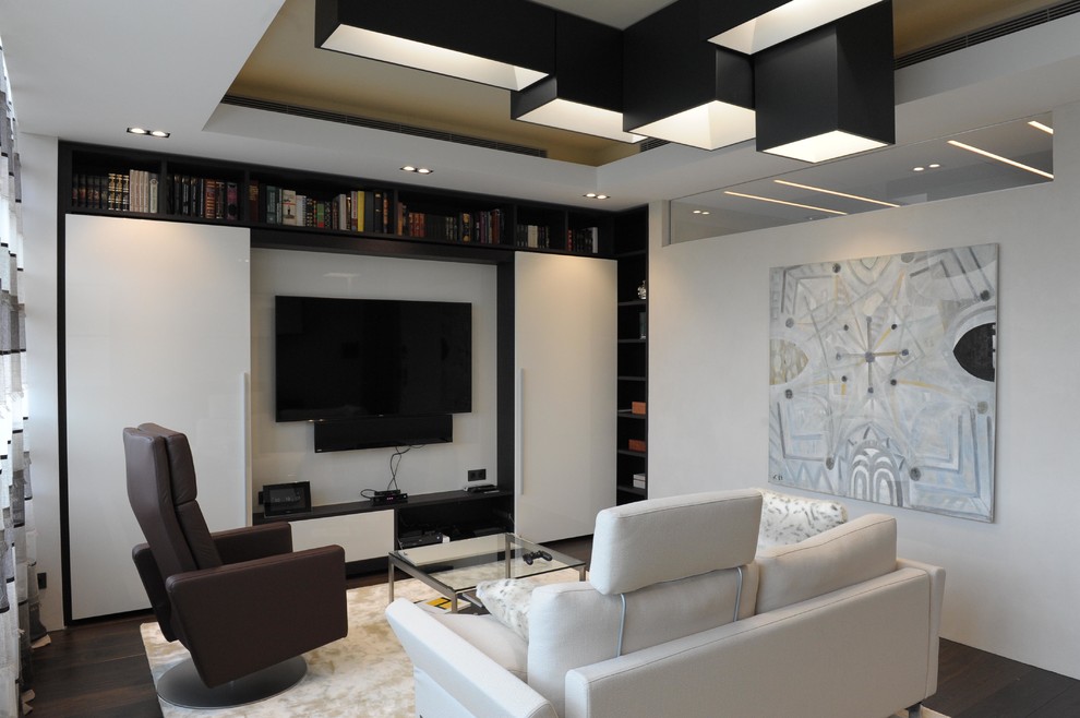 Cette image montre un salon design de taille moyenne et fermé avec une bibliothèque ou un coin lecture, un mur beige, un sol en bois brun et un téléviseur fixé au mur.