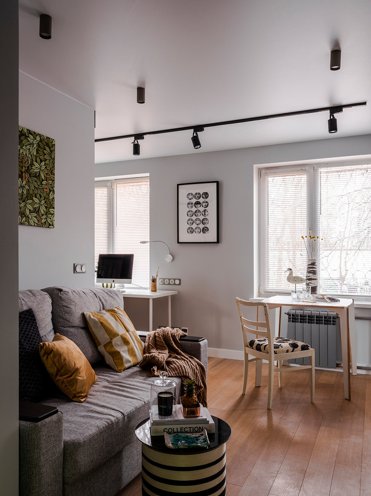 Стильный дизайн: гостиная комната в современном стиле с серыми стенами, паркетным полом среднего тона и коричневым полом - последний тренд