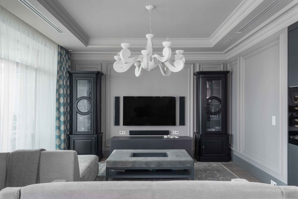 На фото: открытая гостиная комната среднего размера в стиле неоклассика (современная классика) с серыми стенами, паркетным полом среднего тона, телевизором на стене и серым полом с