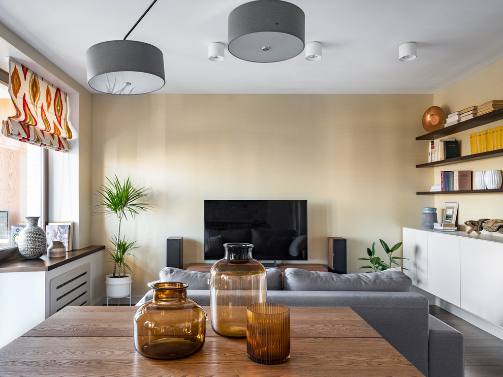 Imagen de salón abierto actual de tamaño medio sin chimenea con paredes beige, suelo laminado, televisor independiente y suelo marrón