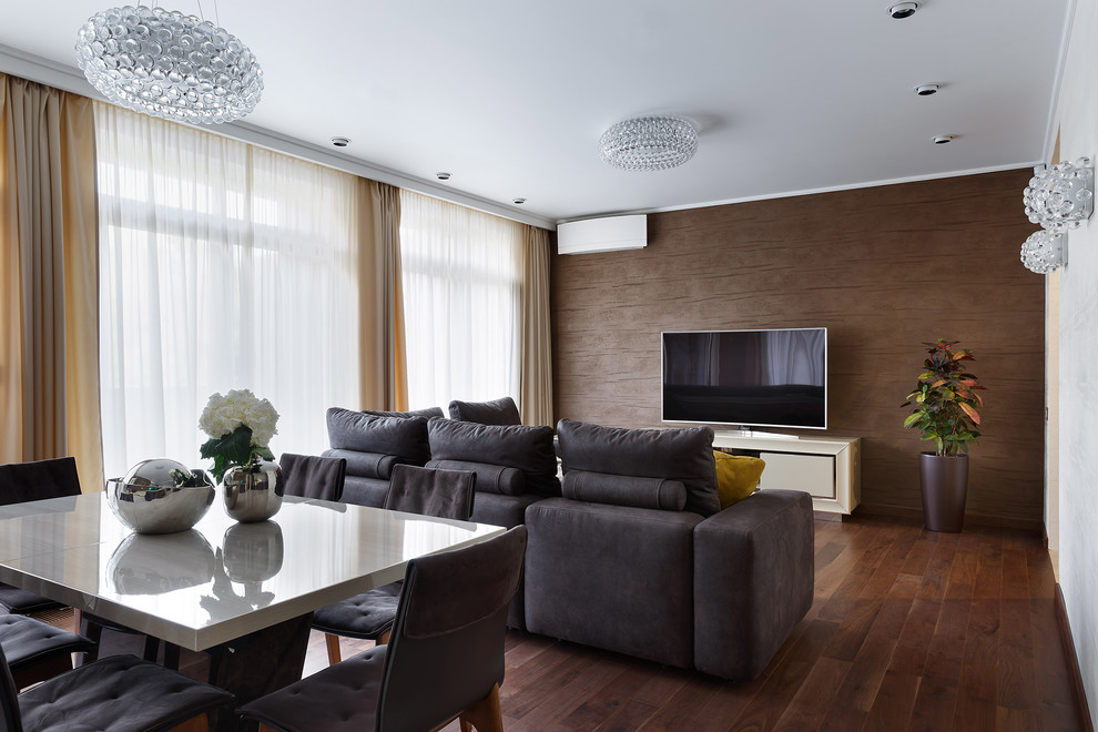 Modern inredning av ett mellanstort allrum med öppen planlösning, med bruna väggar, mellanmörkt trägolv, en fristående TV och brunt golv