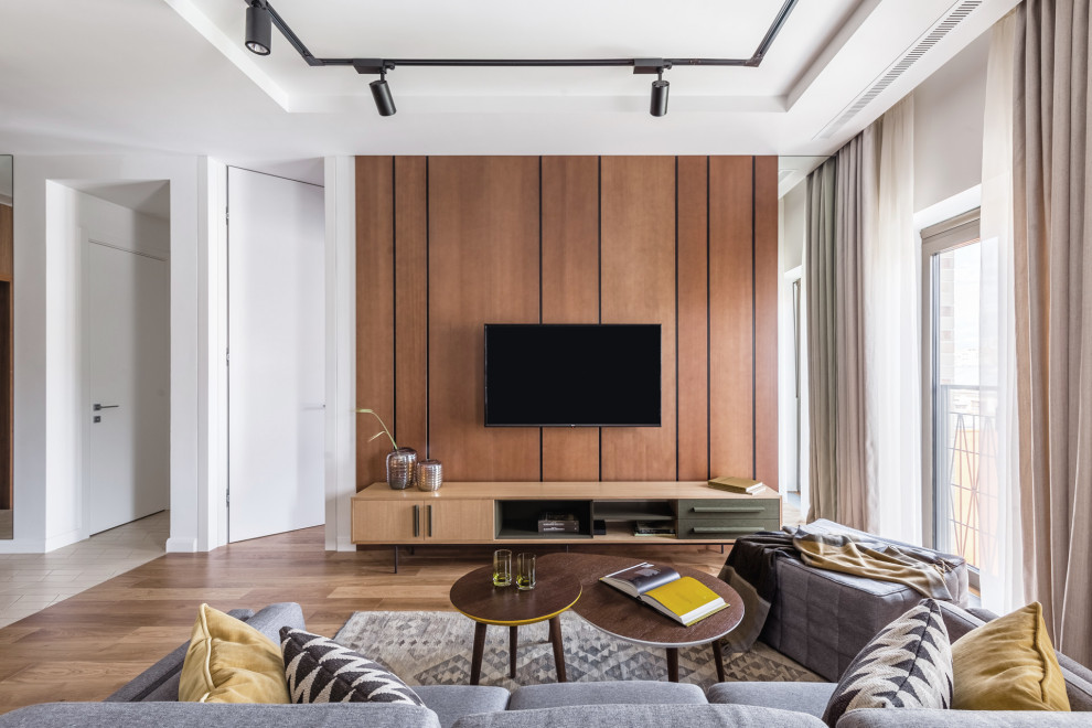 Ejemplo de salón abierto escandinavo de tamaño medio sin chimenea con paredes blancas, suelo de madera en tonos medios, televisor colgado en la pared, suelo marrón y bandeja