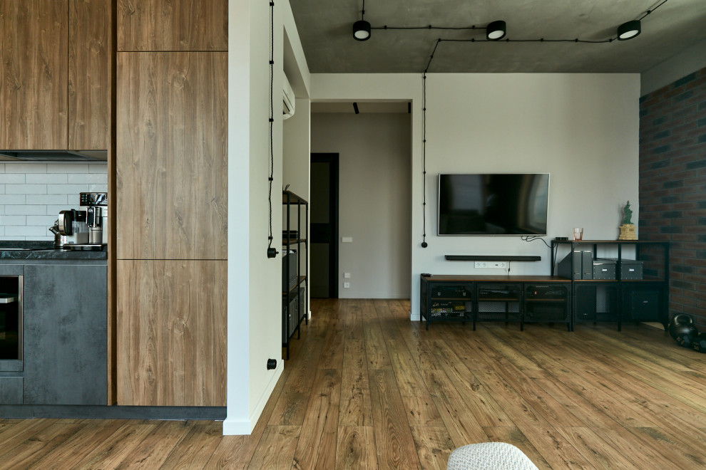 Стильный дизайн: открытая гостиная комната среднего размера в стиле лофт с белыми стенами, паркетным полом среднего тона и телевизором на стене - последний тренд
