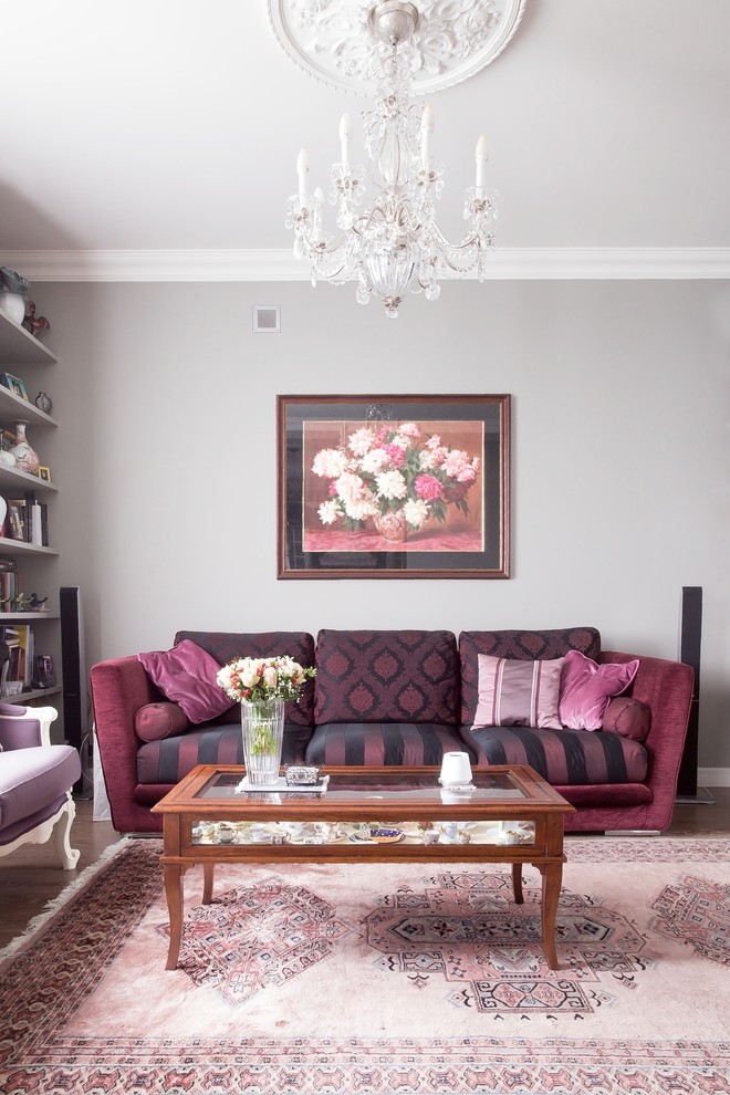 Стильный дизайн: гостиная комната в классическом стиле с серыми стенами, темным паркетным полом и бордовым диваном - последний тренд