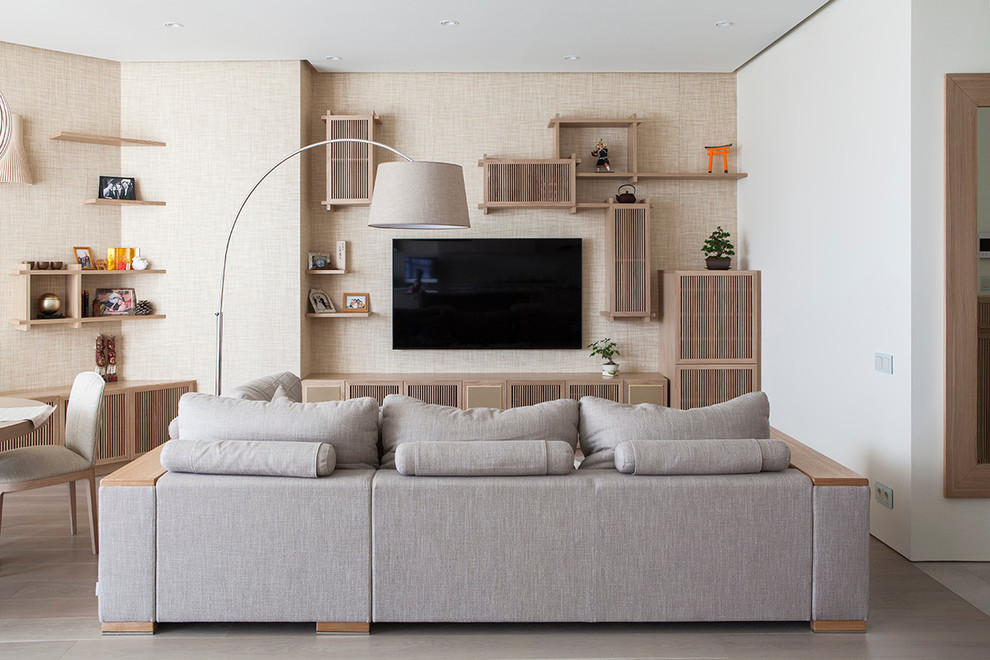 Modern inredning av ett allrum med öppen planlösning, med ett finrum, beige väggar, ljust trägolv och en väggmonterad TV