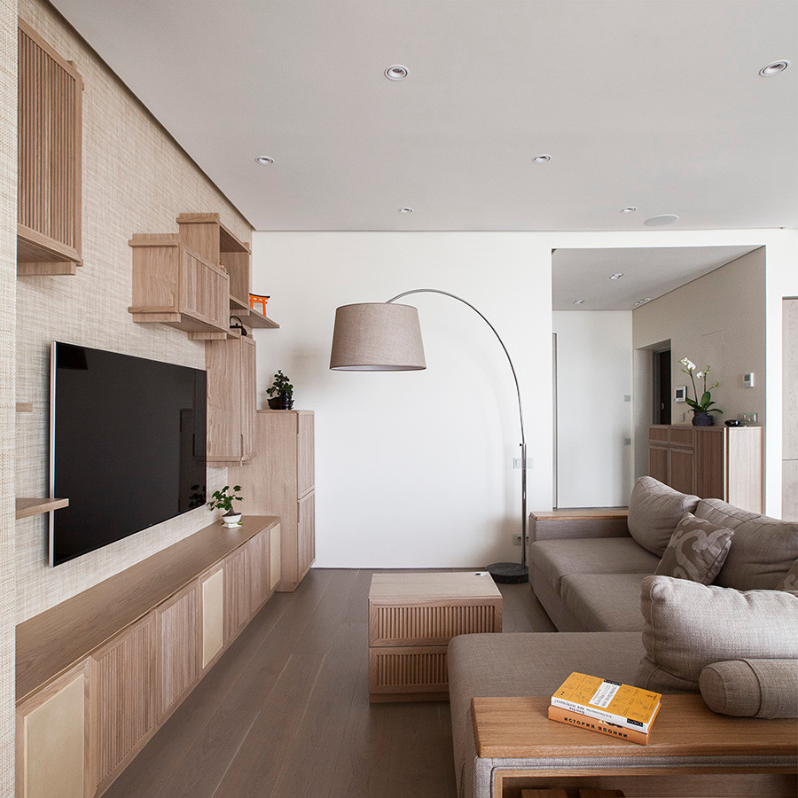 На фото: парадная, открытая гостиная комната в современном стиле с бежевыми стенами, светлым паркетным полом и телевизором на стене без камина