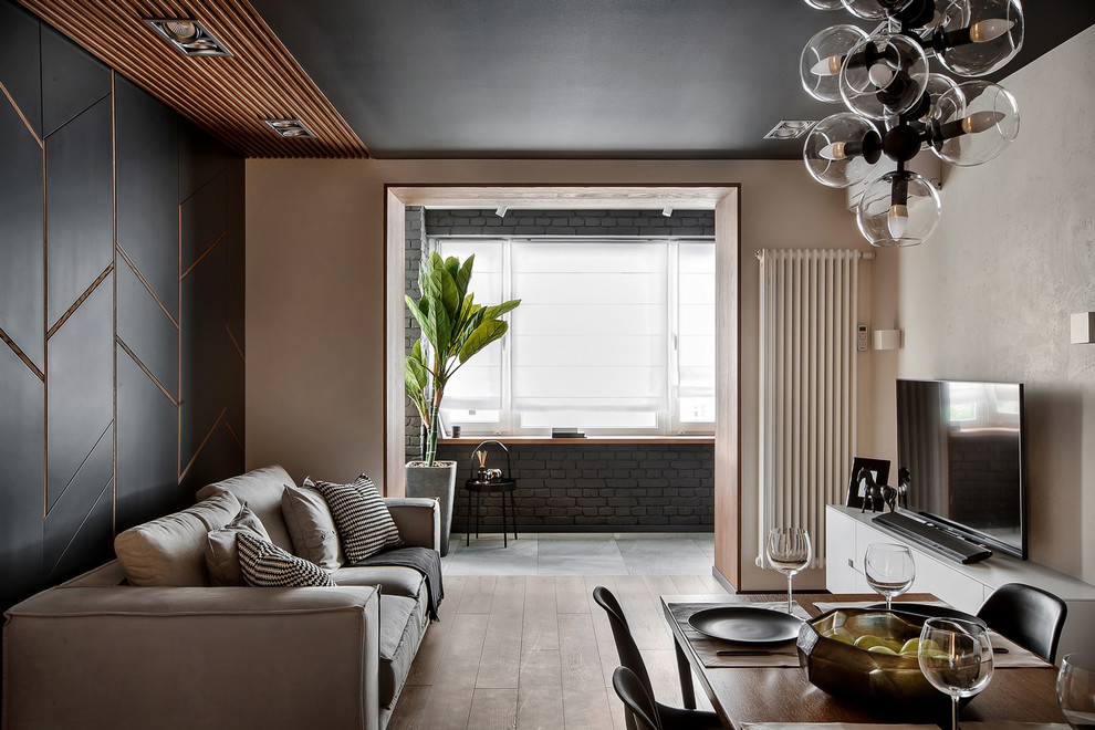 Стильный дизайн: гостиная комната в современном стиле с бежевыми стенами, паркетным полом среднего тона, коричневым полом и акцентной стеной - последний тренд