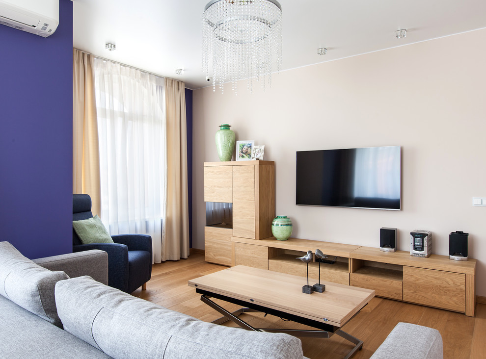 Diseño de salón contemporáneo con paredes beige, suelo de madera en tonos medios, televisor colgado en la pared y suelo marrón