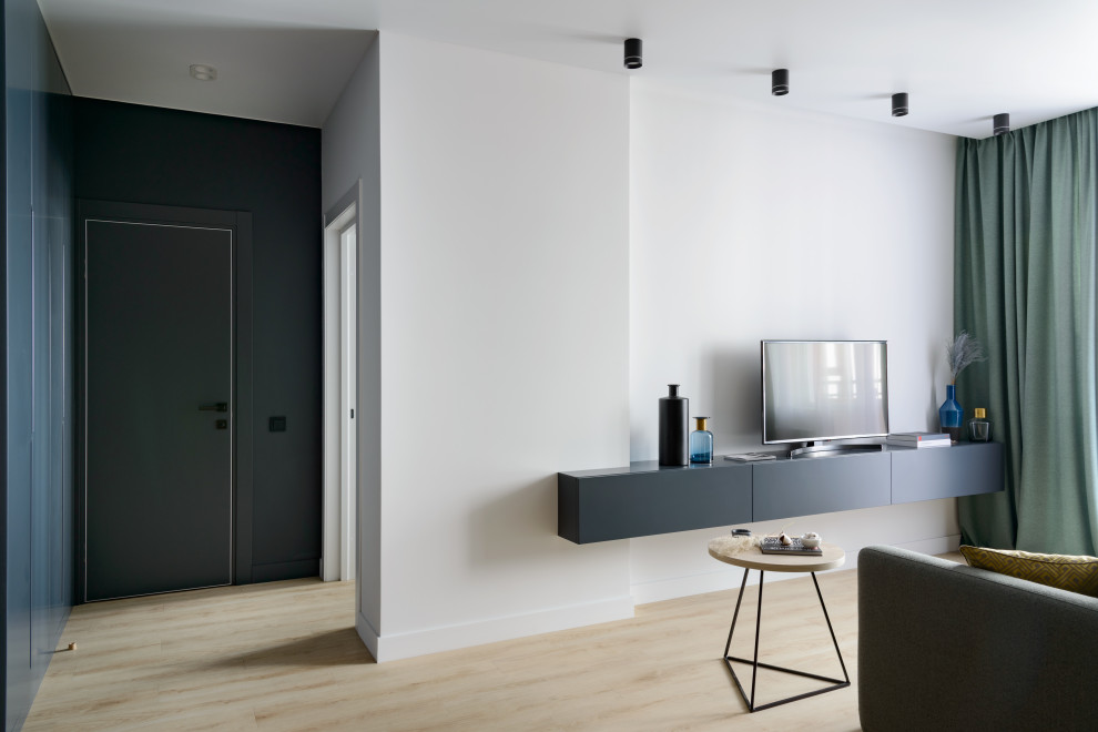 Пример оригинального дизайна: открытая гостиная комната среднего размера в современном стиле с белыми стенами, полом из ламината и отдельно стоящим телевизором