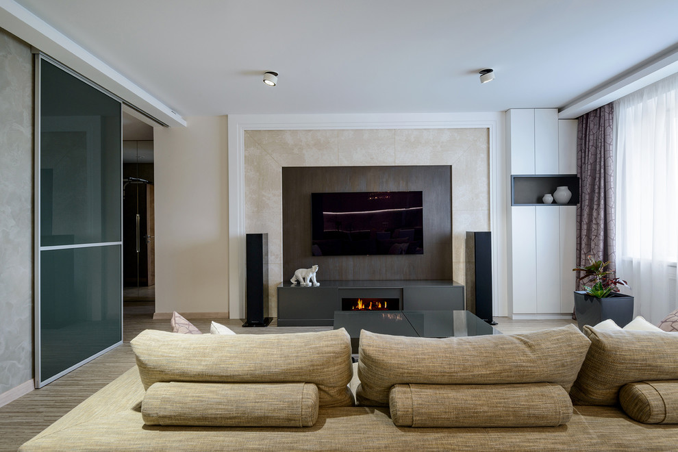Modern inredning av ett mellanstort allrum med öppen planlösning, med beige väggar, korkgolv, en bred öppen spis, en väggmonterad TV och beiget golv