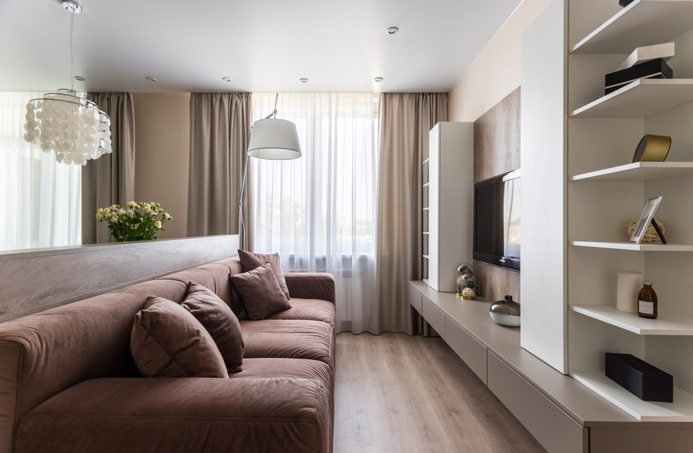 Immagine di un soggiorno minimal con pareti beige, pavimento in legno massello medio, TV a parete e pavimento marrone
