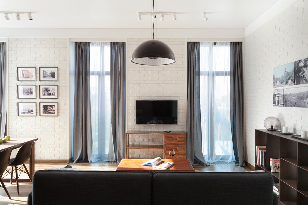 Стильный дизайн: большая открытая гостиная комната в современном стиле с белыми стенами, паркетным полом среднего тона, телевизором на стене и тюлем на окнах - последний тренд