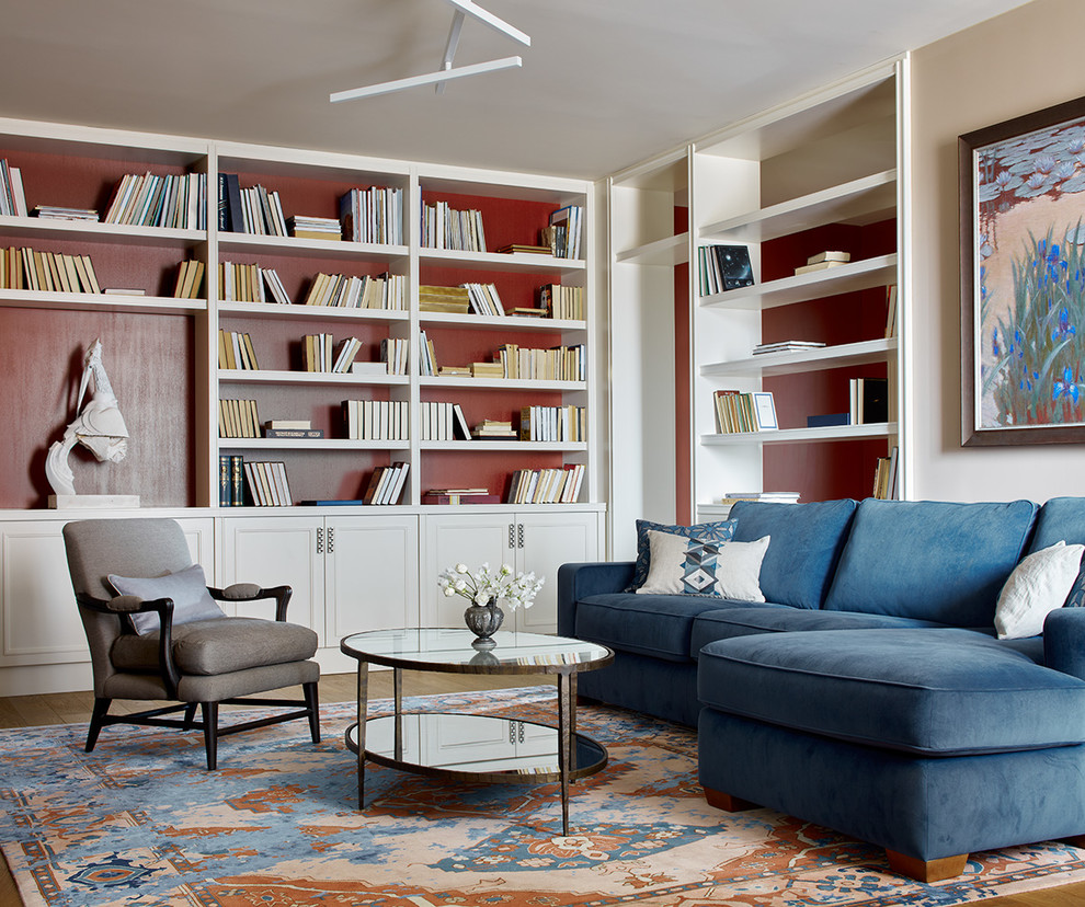 高級な中くらいなトランジショナルスタイルのおしゃれな応接間 (赤い壁、無垢フローリング、茶色い床、青いソファ) の写真