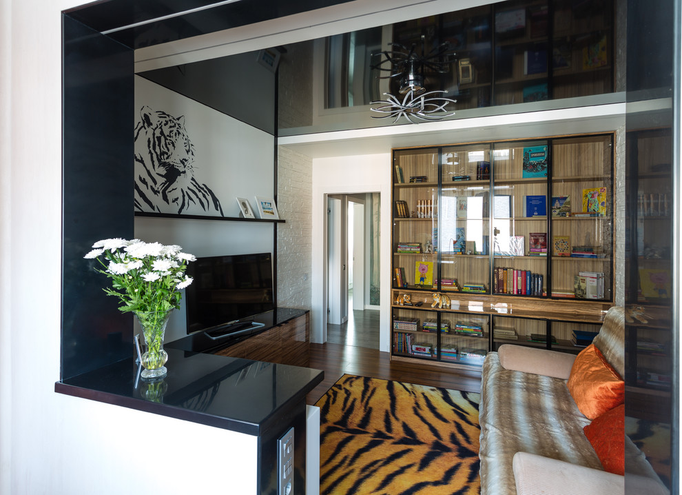 Immagine di un soggiorno design di medie dimensioni con libreria, pareti bianche, pavimento in bambù, nessun camino, TV autoportante e pavimento marrone