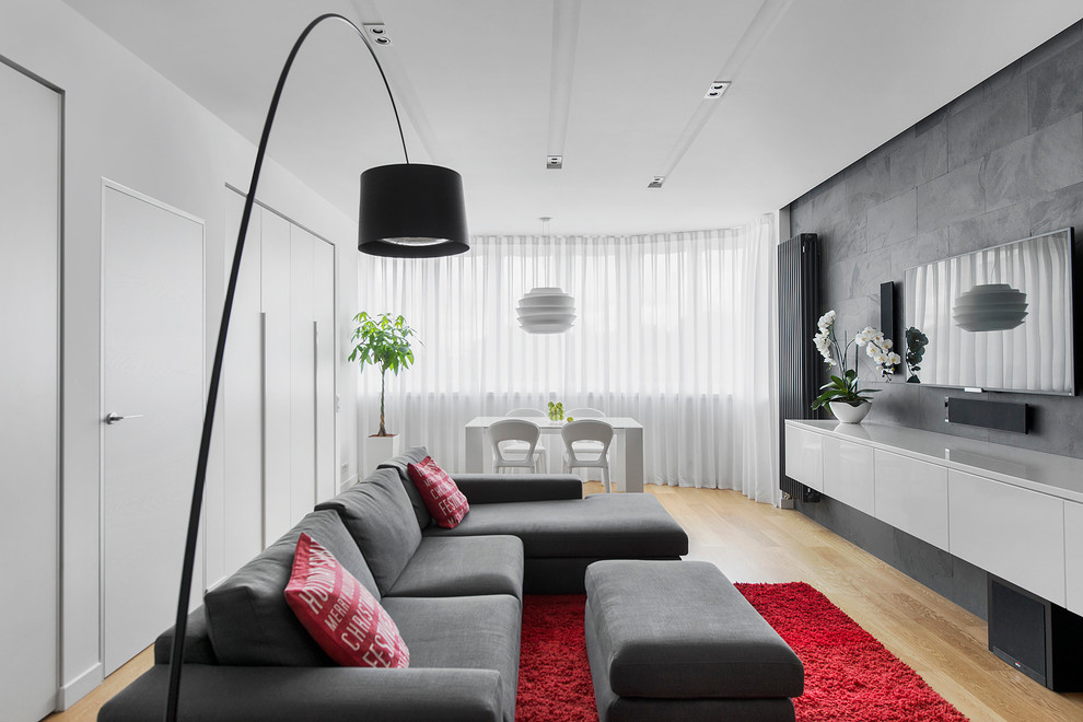 Modern inredning av ett allrum med öppen planlösning, med ett finrum, flerfärgade väggar, ljust trägolv och en väggmonterad TV