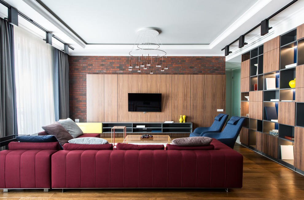 На фото: открытая гостиная комната в современном стиле с коричневыми стенами, паркетным полом среднего тона, телевизором на стене, коричневым полом и бордовым диваном без камина с