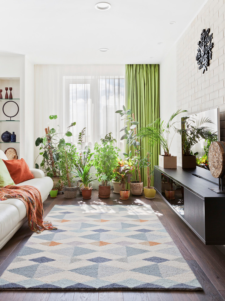 Стильный дизайн: гостиная комната в современном стиле с белыми стенами, темным паркетным полом, коричневым полом и отдельно стоящим телевизором - последний тренд