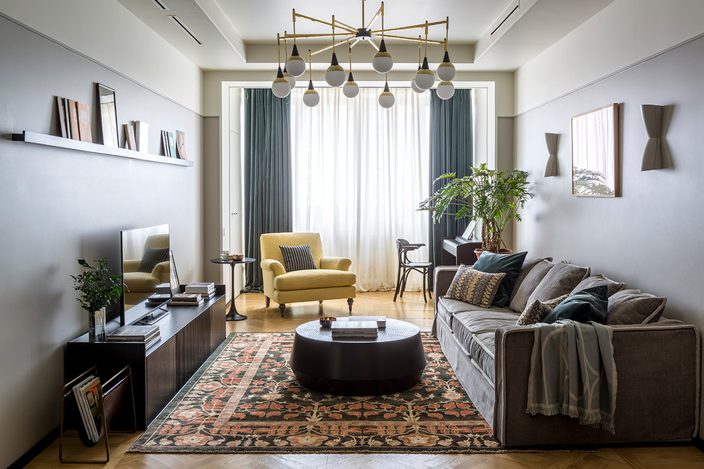 Mittelgroßes Modernes Wohnzimmer ohne Kamin mit grauer Wandfarbe, braunem Holzboden und freistehendem TV in Moskau