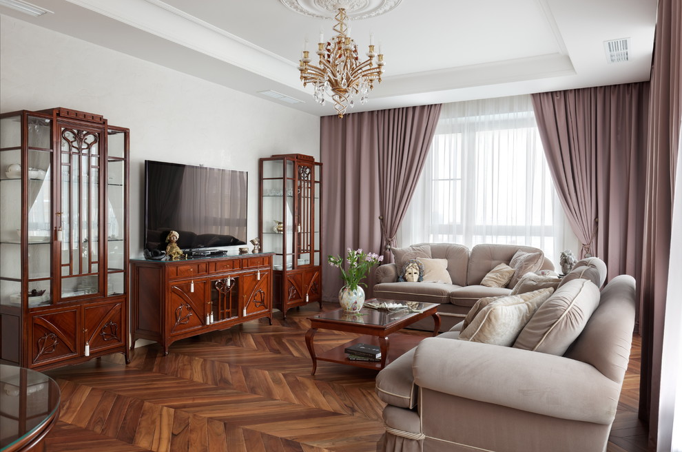 На фото: гостиная комната в классическом стиле с белыми стенами, паркетным полом среднего тона и отдельно стоящим телевизором с