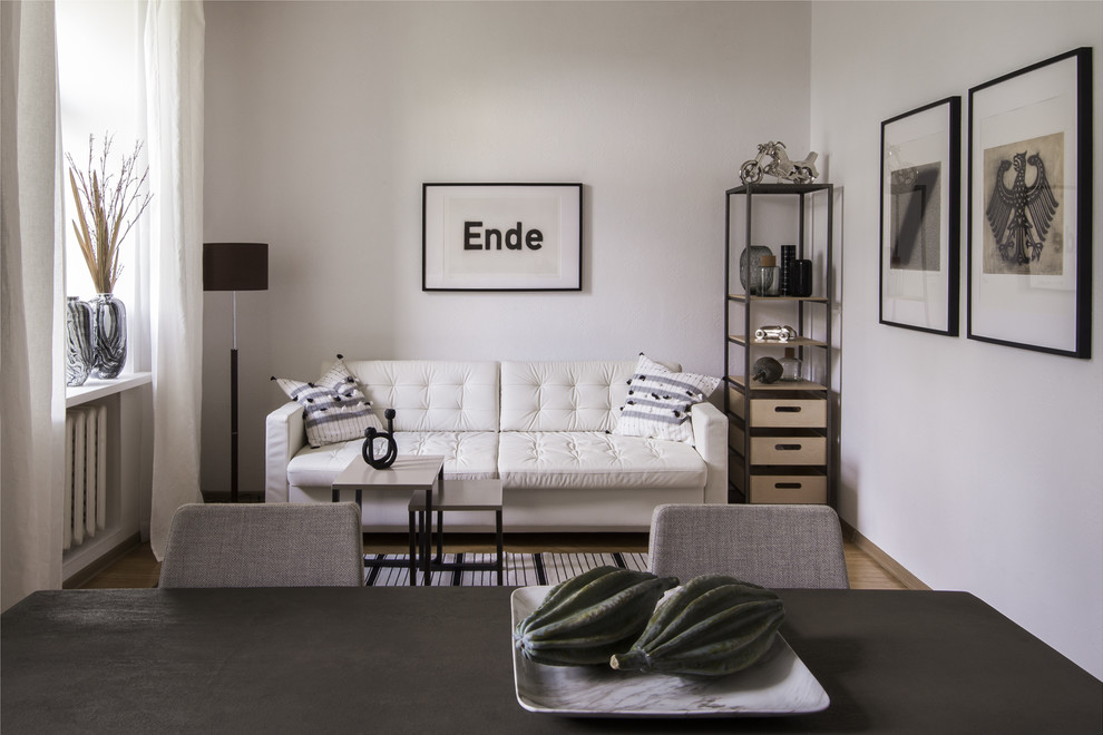Пример оригинального дизайна: открытая гостиная комната в скандинавском стиле с белыми стенами, светлым паркетным полом и коричневым полом без телевизора