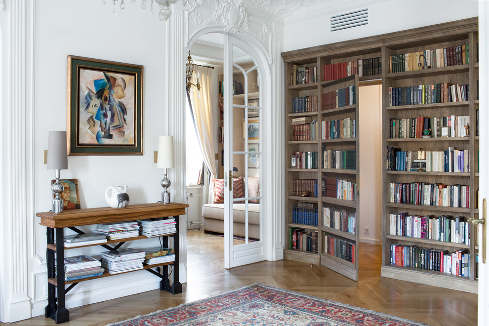 Stilmix Bibliothek mit weißer Wandfarbe, braunem Holzboden und braunem Boden in Moskau