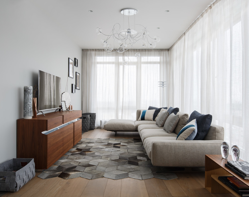 Modelo de sala de estar actual grande sin chimenea con suelo de madera en tonos medios, televisor independiente y paredes grises