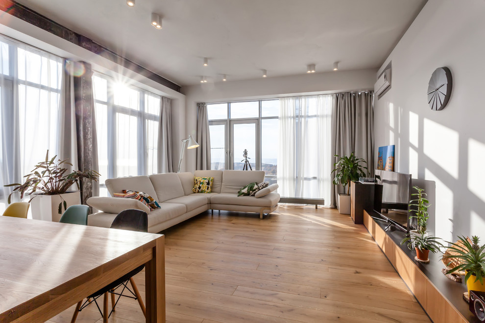 На фото: гостиная комната в скандинавском стиле с белыми стенами и паркетным полом среднего тона без камина