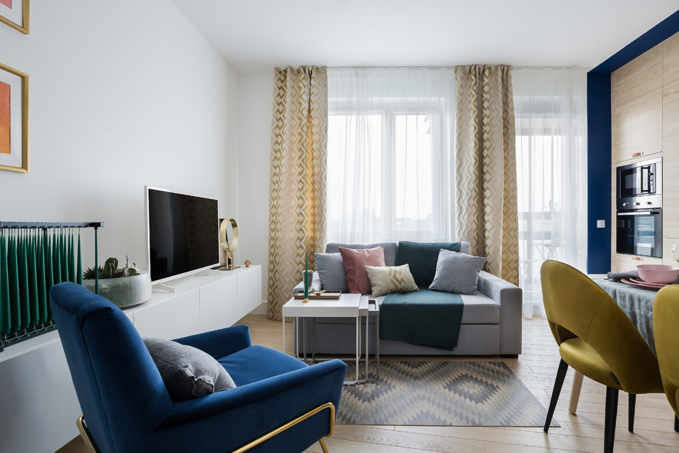 На фото: открытая, объединенная гостиная комната среднего размера в скандинавском стиле с белыми стенами, светлым паркетным полом, отдельно стоящим телевизором и тюлем на окнах без камина