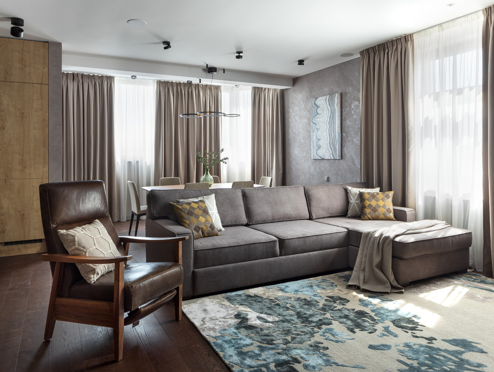 На фото: большая открытая гостиная комната в современном стиле с серыми стенами, паркетным полом среднего тона, телевизором на стене и коричневым полом с