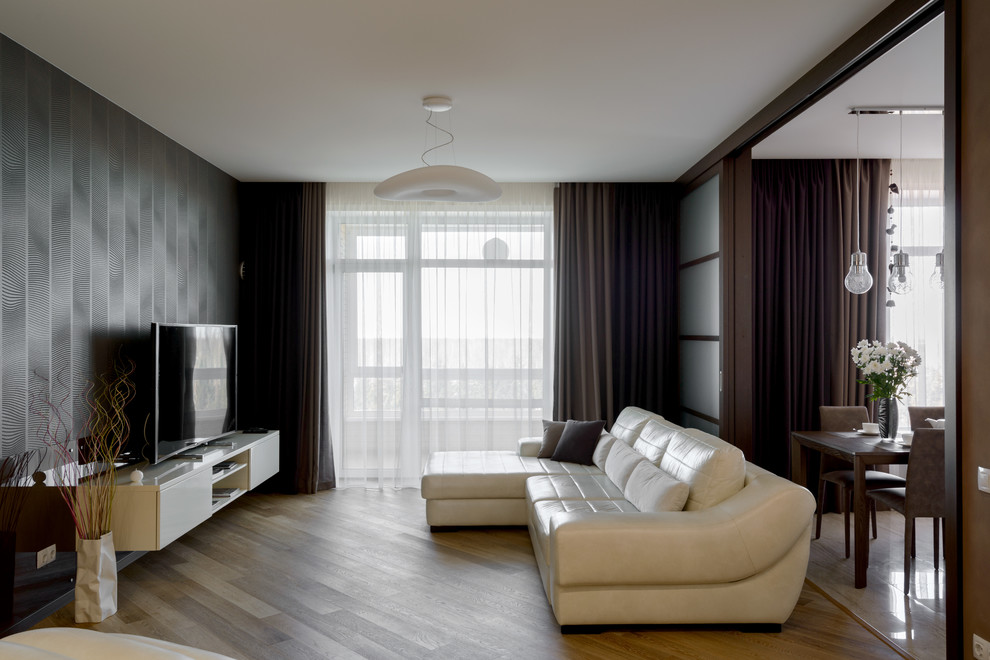 На фото: большая открытая, объединенная гостиная комната в современном стиле с коричневыми стенами, полом из ламината, подвесным камином, фасадом камина из металла и отдельно стоящим телевизором