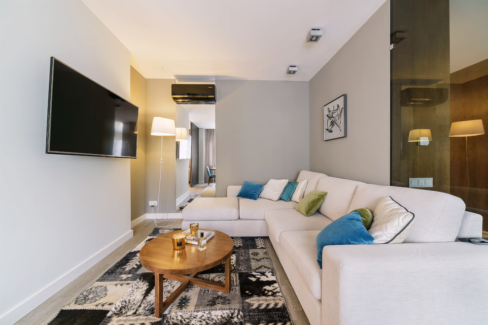 На фото: гостиная комната в современном стиле с серым полом, белыми стенами, светлым паркетным полом и телевизором на стене