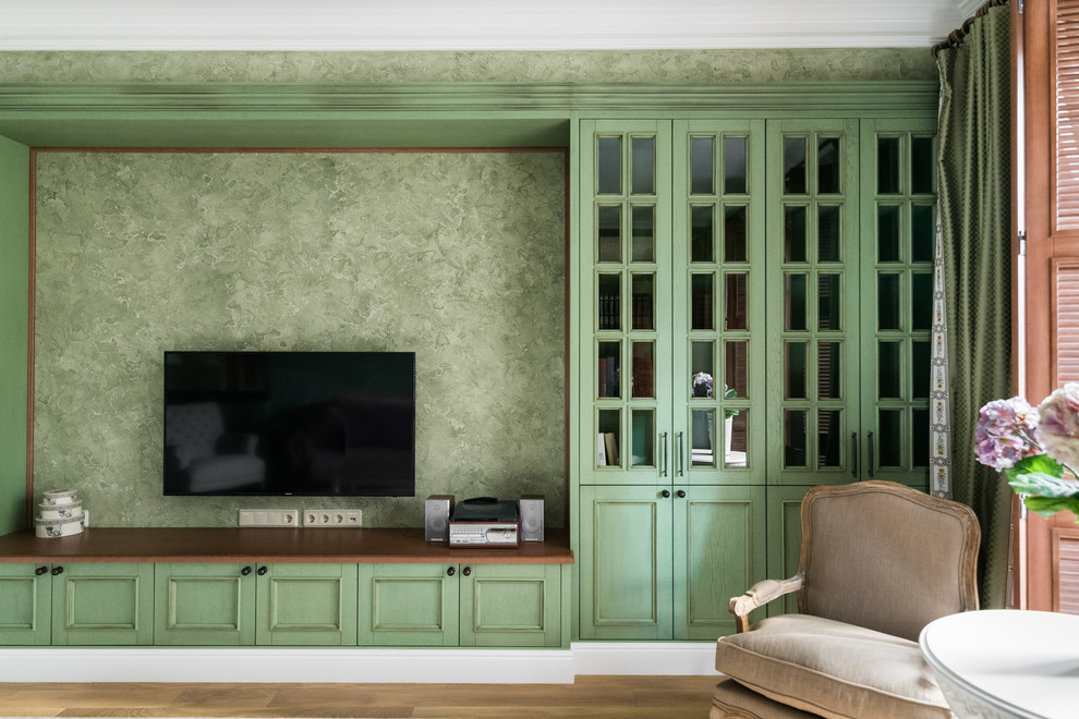 Diseño de salón tradicional renovado con paredes verdes, televisor colgado en la pared y suelo marrón