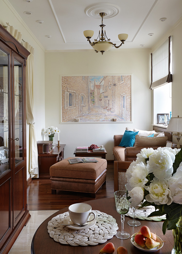 На фото: гостиная комната в классическом стиле с желтыми стенами, темным паркетным полом, коричневым полом и коричневым диваном с
