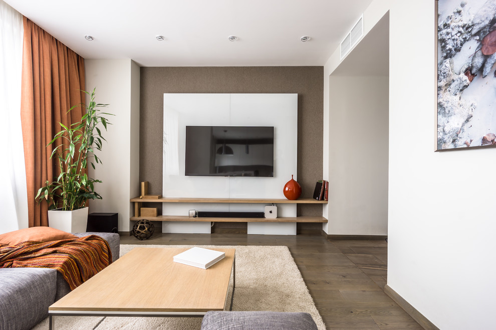 Foto på ett mellanstort funkis allrum med öppen planlösning, med vita väggar, mellanmörkt trägolv, en väggmonterad TV och brunt golv