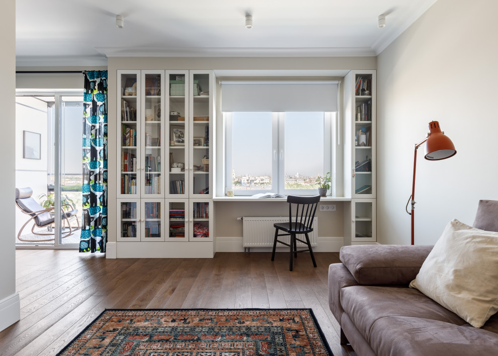 Стильный дизайн: открытая, объединенная гостиная комната среднего размера в скандинавском стиле с с книжными шкафами и полками, бежевыми стенами, деревянным полом, мультимедийным центром и коричневым полом - последний тренд