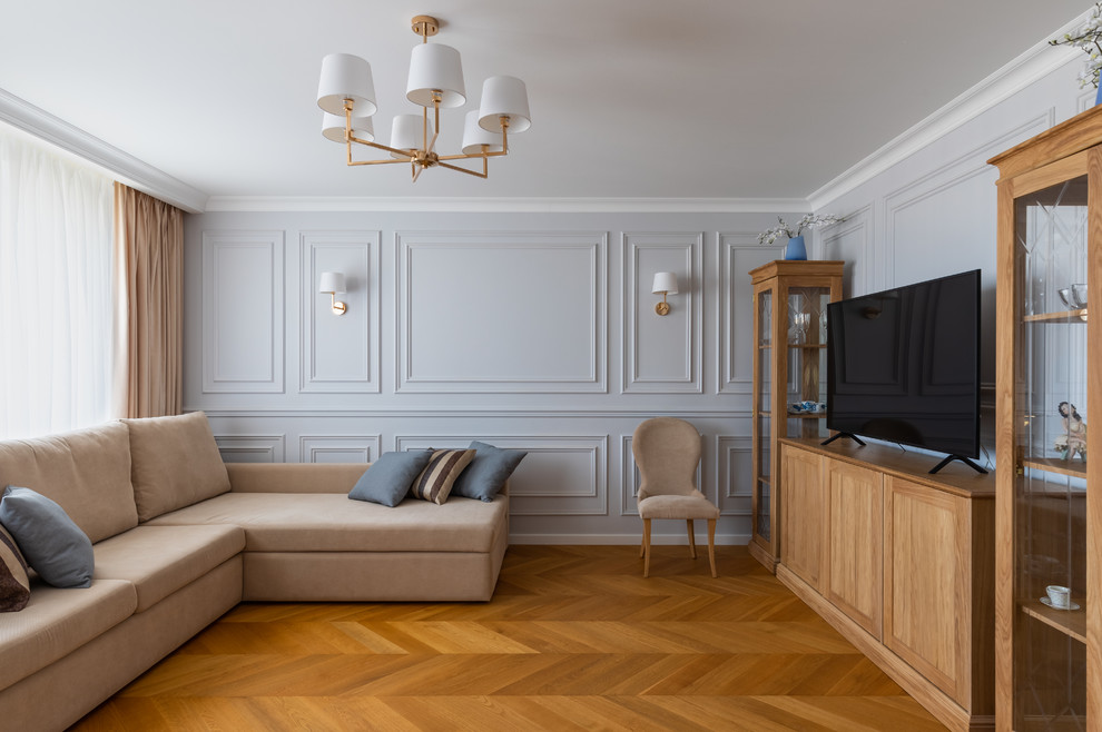 Пример оригинального дизайна: парадная гостиная комната в стиле неоклассика (современная классика) с серыми стенами, паркетным полом среднего тона, отдельно стоящим телевизором и коричневым полом